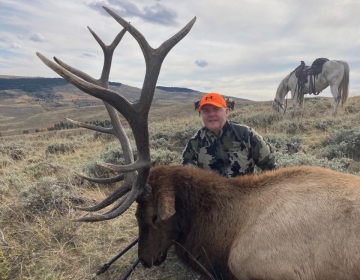Wyoming non resident hunter with his bull elk and horse in the background
